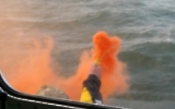 Seenotfackel / orangefarbene Rauchfackel auf hoher See vor Holland