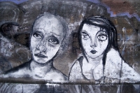 zwei traurige Gesichter auf einer Mauer, Graffiti in Berlin Neukölln