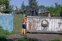 Kind vor einem Holztor mit Schnitzereien in Sibirien