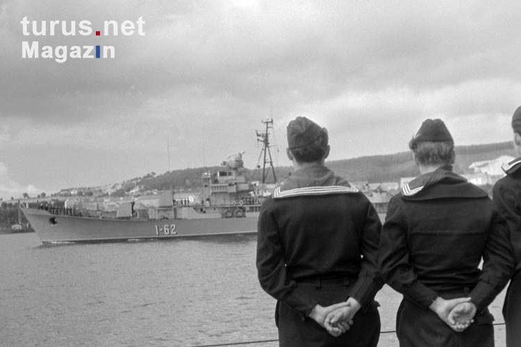 Soldaten der DDR-Volksmarine nehmen Aufstellung, im Hintergrund ein Schiff im Hafen