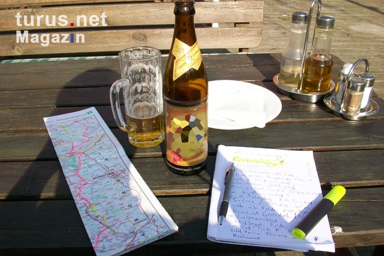 Reiseplanung mit einer Landkarte, einem Notizblock und einer Flasche Bier