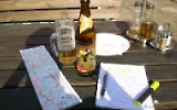 Reiseplanung mit einer Landkarte, einem Notizblock und einer Flasche Bier